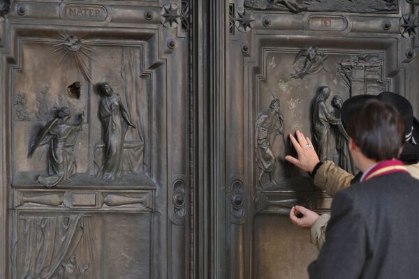 People stand by the entrance door of the papal basilica of Santa Maria Maggiore (Saint Mary Major) after a vandal attacked the bronze and wooden door with a stone and damaged the portrayal of the Annunciation to to the Virgin Mary (L) on December 19, 2011 in Rome.  - Sputnik Казахстан