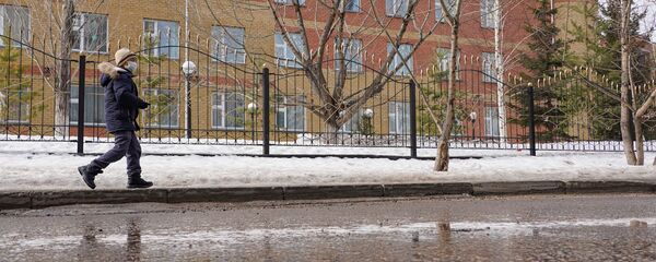 Ребенок в маске проходит рядом со школой во время каникул - Sputnik Казахстан