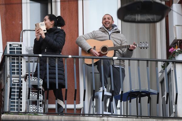 A man plays the guitar from a balcony to raise morale on the sixth day of an unprecedented lockdown across of all Italy imposed to slow the outbreak of coronavirus in Milan, Italy March 15, 2020.  - Sputnik Казахстан