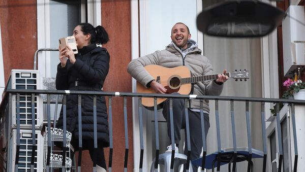 Мужчина с гитарой и женщина со смартфоном на одном из балконов в Милане - Sputnik Казахстан