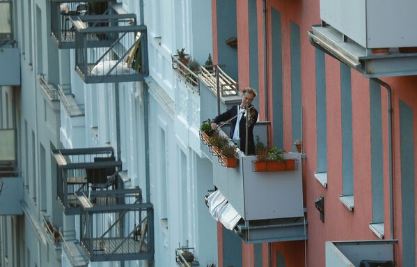 A man plays the violin from a balcony to raise morale as German government is preparing to close borders and schools to halt the spread of COVID-19 coronavirus outbreak in Berlin, Germany March 15, 2020. - Sputnik Казахстан