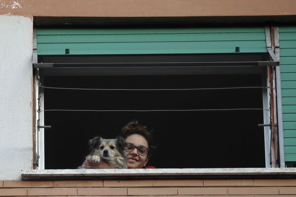 A girl and her dog look out from a window during one of the many flash mobs taking place these days in Rome, Sunday, March 15, 2020. The nationwide lockdown to slow coronavirus is still early days for much of Italy, but Italians are already showing signs of solidarity with flash mob calls circulating on social media for people to ''gather'' on their balconies at certain hours, either to play music or to give each other a round of applause. For most people, the new coronavirus causes only mild or moderate symptoms. For some, it can cause more severe illness, especially in older adults and people with existing health problems.  - Sputnik Казахстан