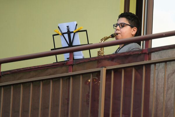 Мальчик играет на саксофоне на балконе своего дома во время карантина в Милане - Sputnik Казахстан