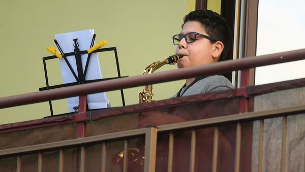 Мальчик играет на саксофоне на балконе своего дома во время карантина в Милане - Sputnik Казахстан
