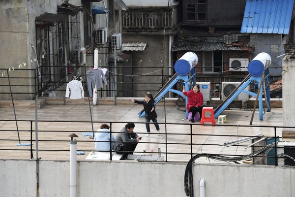 A child plays next to adults sitting on the roof terrace of a building at a residential compound in Wuhan, the epicentre of the novel coronavirus disease (COVID-19) outbreak, Hubei province, China, March 4, 2020.   - Sputnik Казахстан