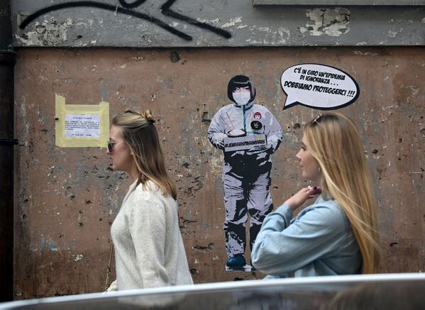 Two women walk by a mural painting reading There's an epidemic of ignorance in the air, we must protect ourselves ! referring to the coronavirus outbreak by the street artist Laika near the Chinese district in Rome, on February 04, 2020.  - Sputnik Казахстан