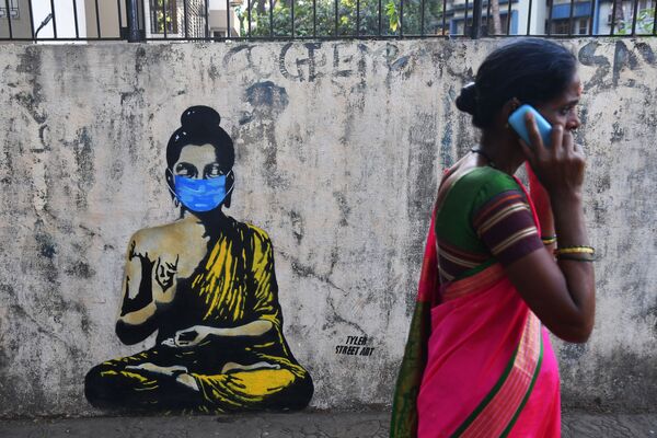A resident walks past a graffiti of Lord Gautam Buddha wearing facemask amid concerns over the spread of the COVID-19 novel coronavirus, in Mumbai on March 16, 2020.  - Sputnik Казахстан