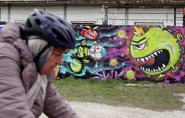A cyclist passes a graffiti depicting the coronavirus in Budapest, Hungary, March 25, 2020. REUTERS/Bernadett Szabo NO RESALES. NO ARCHIVES - Sputnik Казахстан