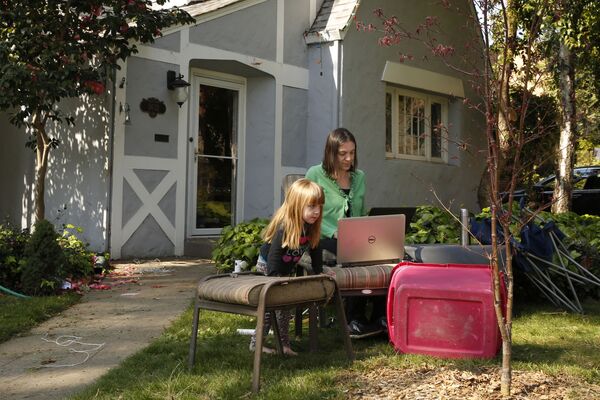 
Alison Steffensen is joined by her daughter, Elin, 3, as she works at the home office she set up in the front yard of her home in Sacramento, Calif., Friday, March 20, 2020. Steffensen, a psychologist who works for Yolo County, is adjusting to Gov. Gavin Newsom's stay-at-home order, issued Thursday, to slow the spread of the coronavirus. - Sputnik Казахстан