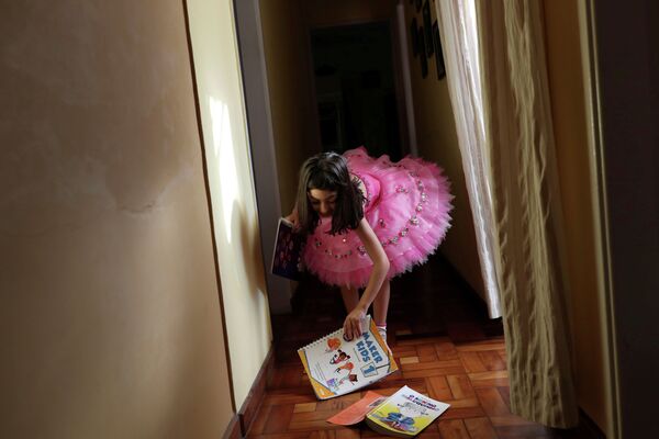Alice, 5, grabs her books that fell down after her daily study session at home during a lockdown imposed by the state government because of the coronavirus disease (COVID-19) outbreak in Santo Andre, Brazil, March 26, 2020. REUTERS/Amanda Perobelli     TPX IMAGES OF THE DAY - Sputnik Казахстан