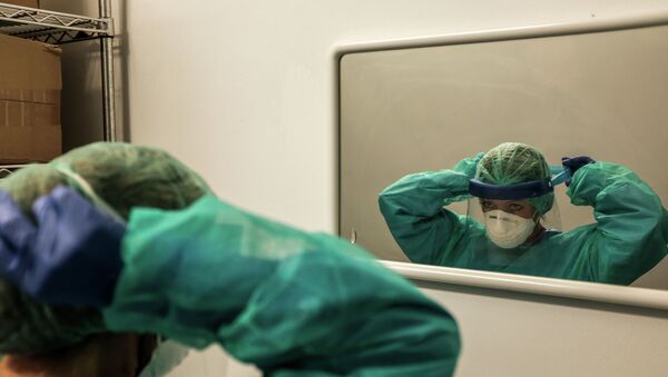 Врач надевает защитный костюм перед зеркалом в больнице с коронавирусом - Sputnik Қазақстан