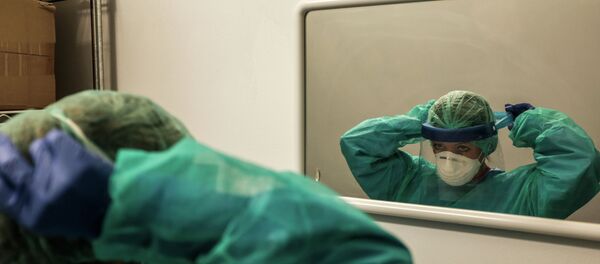 Врач надевает защитный костюм перед зеркалом в больнице с коронавирусом - Sputnik Казахстан