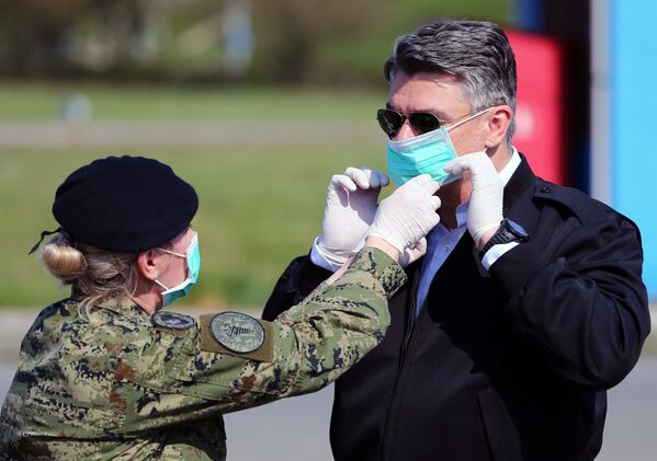 A soldier helps Croatia's President Zoran Milanovic to wear a face mask before he visits the tents which are built for patients who will have coronavirus disease (COVID-19) at Dubrava hospital in Zagreb, Croatia, March 21, 2020.  - Sputnik Казахстан