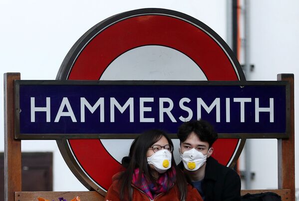 Пара в защитных масках у станции метро Hammersmith в Лондоне - Sputnik Казахстан