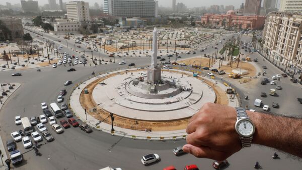 Показывающие полдень наручные часы на фоне пустой площади Тахрир в Каире в период пандемии коронавируса - Sputnik Казахстан