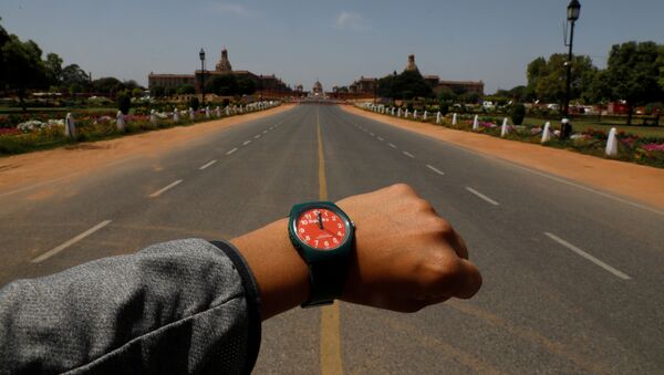 Показывающие полдень наручные часы на фоне пустого проспекта Раджпатх в Нью-Дели в период пандемии коронавируса - Sputnik Казахстан