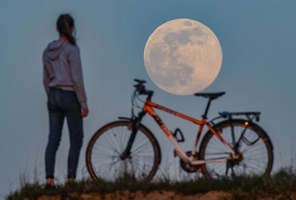 Девушка с велосипедом наблюдает за суперлунием в Зиверсдорфе, Германия - Sputnik Казахстан
