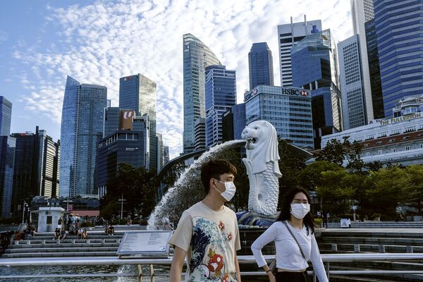 Пара в масках у статуи Мерлиона в Сингапуре - Sputnik Казахстан