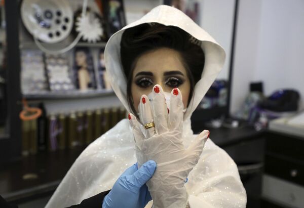 Palestinian bride Baraa shows off her ring over a glove at a salon in the West Bank village of Dora near Hebron on April 4, 2020, ahead of the wedding ceremony at home as authorities imposed restrictions on large gatherings in a bid to stem the spread of the COVID-19 coronavirus.  - Sputnik Казахстан