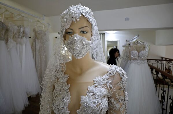 A mannequin displays an embroidered protective mask with the matching wedding dress at the workshop of designer Lobna Safadi (background) in the Druze village of Majdal Shams in the Israel-annexed Golan Heights, on April 3, 2020, amid the novel coronavirus epidemic.  - Sputnik Казахстан