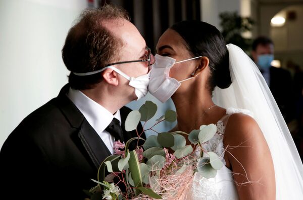 Newlyweds Diego Fernandes, 46 and Deni Salgado, 30, kiss through protective face masks at a wedding ceremony with only witnesses and no guests, as public gatherings are banned as part of Italy's lockdown measures to prevent the spread of coronavirus disease (COVID-19) in Naples, Italy, March 20, 2020.  - Sputnik Казахстан