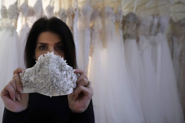 Wedding dress designer Lobna Safadi from the Druze village of Majdal Shams in the Israel-annexed Golan Heights displays an embroidered protective mask matching one of her designs at her workshop in the village, on April 3, 2020, amid the novel coronavirus epidemic.  - Sputnik Казахстан