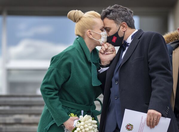 Newlyweds Alla and Modzi kiss through protective face masks after the wedding ceremony with only witnesses, as public gatherings are banned as part of Lithuania's lockdown measures to prevent the spread of coronavirus disease (COVID-19) in Vilnius, Lithuania, Friday, April 3, 2020. All public and private events are banned in Lithuania, clubs, bars restaurants and most shops are closed due to the virus outbreak. The new coronavirus causes mild or moderate symptoms for most people, but for some, especially older adults and people with existing health problems, it can cause more severe illness or death.  - Sputnik Казахстан