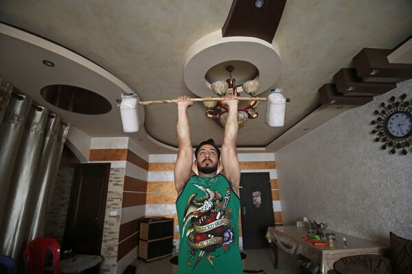 Палестинский тренер по фитнесу и бодибилдингу Ахмед Сави во время тренировки у себя дома - Sputnik Казахстан
