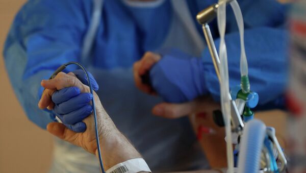 Врач держит руки пациента в больнице с коронавирусом  - Sputnik Қазақстан