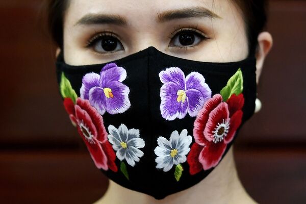 A model poses wearing designer Do Quyen Hoa's colourful hand-embroidered face masks, used as a preventive measure against the spread of the COVID-19 novel coronavirus, at her workshop in Hanoi on April 13, 2020. (Photo by Nhac NGUYEN / AFP)
 - Sputnik Казахстан