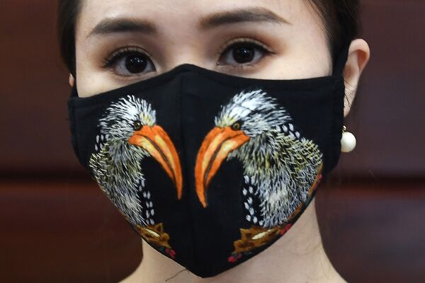A model poses wearing designer Do Quyen Hoa's colourful hand-embroidered face masks, used as a preventive measure against the spread of the COVID-19 novel coronavirus, at her workshop in Hanoi on April 13, 2020. (Photo by Nhac NGUYEN / AFP) - Sputnik Казахстан