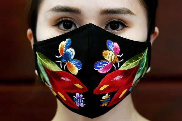 A model poses wearing designer Do Quyen Hoa's colourful hand-embroidered face masks, used as a preventive measure against the spread of the COVID-19 novel coronavirus, at her workshop in Hanoi on April 13, 2020.  - Sputnik Казахстан