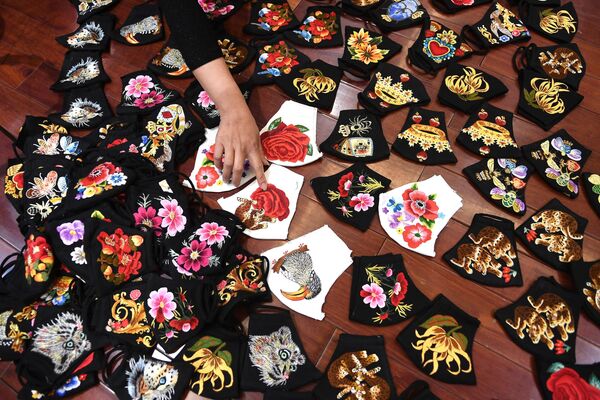 A worker points at colourful hand-embroidered face masks, used as a preventive measure against the spread of the COVID-19 novel coronavirus, at designer Do Quyen Hoa's workshop in Hanoi on April 13, 2020. 
 - Sputnik Казахстан