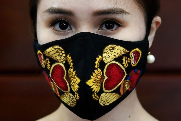 A model poses wearing designer Do Quyen Hoa's colourful hand-embroidered face masks, used as a preventive measure against the spread of the COVID-19 novel coronavirus, at her workshop in Hanoi on April 13, 2020. (Photo by Nhac NGUYEN / AFP) - Sputnik Казахстан