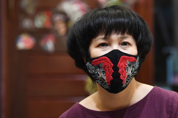 Designer Do Quyen Hoa poses wearing her colourful hand-embroidered face mask creation, used as a preventive measure against the spread of the COVID-19 novel coronavirus, at her workshop in Hanoi on April 13, 2020. (Photo by NGUYEN / AFP) - Sputnik Казахстан