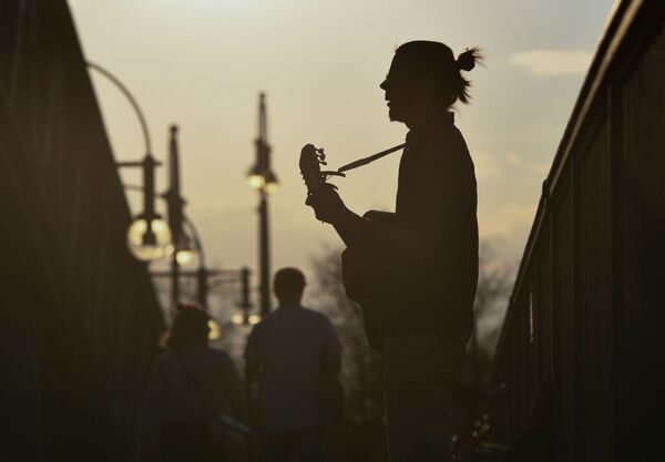 Мужчина играет на гитаре на мосту во время заката в Берлине, Германия - Sputnik Казахстан