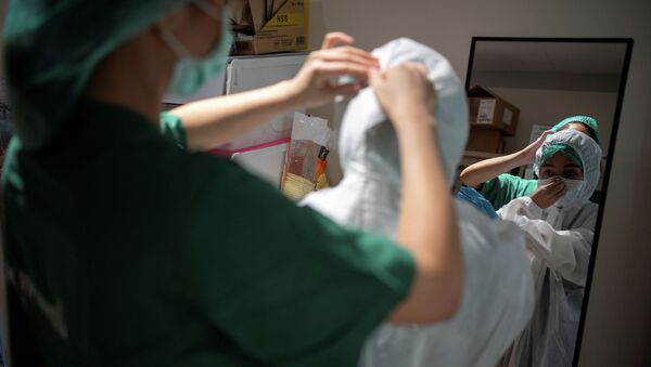 Медсестра помогает коллеге надеть защитный костюм в больнице с коронавирусом - Sputnik Қазақстан