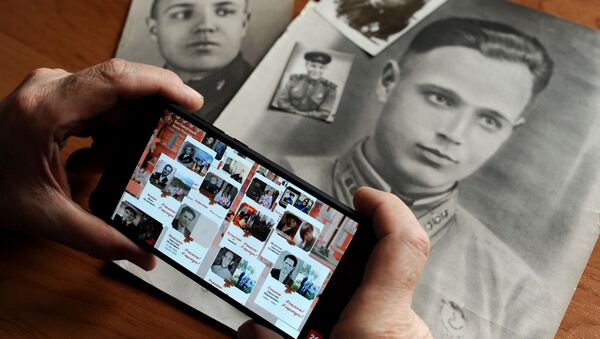 Мужчина смотрит онлайн-трансляцию акции Бессмертный полк - Sputnik Қазақстан