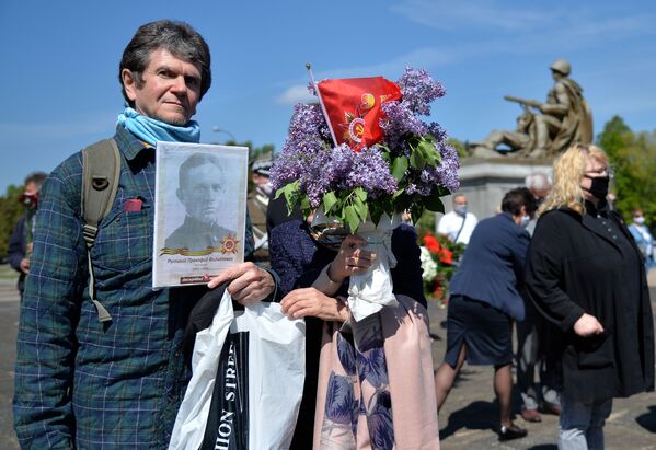 Поляки с портретом ветерана ВОВ и советским флагом в День 75-летия Победы в Великой Отечественной войне в Варшаве - Sputnik Казахстан