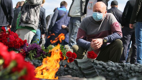 Люди возлагают цветы к Вечному огню у памятника Вечной славы на могиле неизвестного солдата в Киеве в день празднования Дня Победы - Sputnik Казахстан
