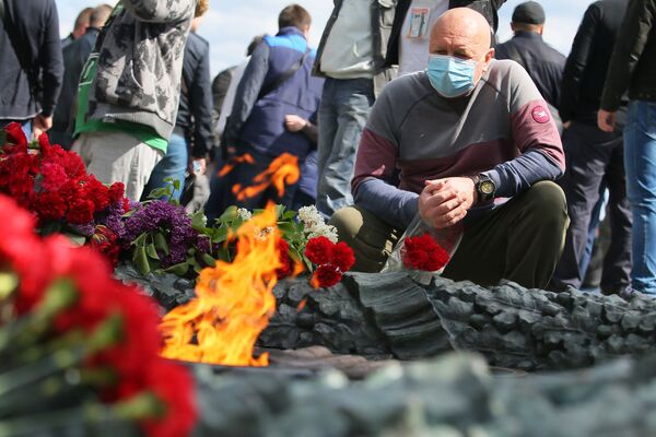 Люди возлагают цветы к Вечному огню у памятника Вечной славы на могиле неизвестного солдата в Киеве в день празднования Дня Победы - Sputnik Казахстан