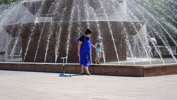 Женщина в маске гуляет с ребенком у фонтана в Нур-Султане - Sputnik Казахстан
