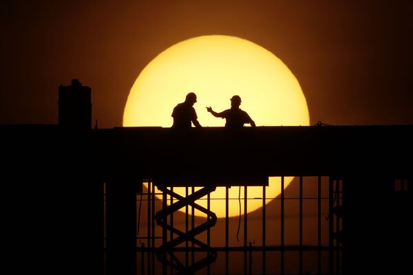 Рабочие на фоне восходящего солнца на стройке в Канзас-сити, штат Миссури, США - Sputnik Казахстан