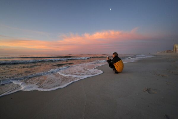Девушка с телефоном на рассвете на пляже в Орандж-Бич, США  - Sputnik Казахстан