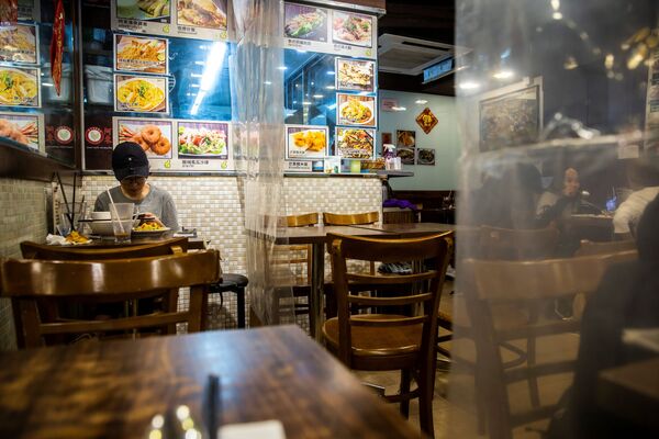 Посетитель ресторана, разделенного пластиковыми полотнами в Гонконге  - Sputnik Казахстан