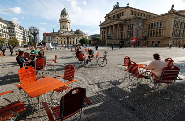 Люди наслаждаются погодой в кафе на площади Жандарменмаркт в Берлине, соблюдая принцип социальной дистанции - Sputnik Казахстан