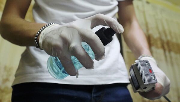 Сотрудница салона красоты обрабатывает антисептиком машинку для стрижки  - Sputnik Казахстан