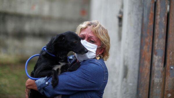 Женщина в защтиной маске держит на руках собаку во время пандемии коронавируса  - Sputnik Казахстан