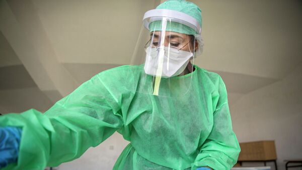 Медик в защитном костюме на мобильном пункте скрининга населения на коронавирус - Sputnik Казахстан