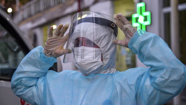 Врач в защитном костюме и перчатках поправляет лицевую маску у больницы с коронавирусом  - Sputnik Казахстан
